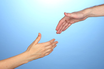 Women's hand goes to the man's hand on blue background
