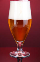 Glass of beer on pink background