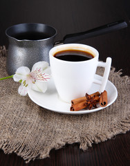 White cup of Turkish coffee with coffee maker on wooden table