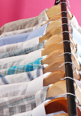 Men's shirts on hangers on pink background