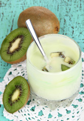 Delicious yogurt in glass with kiwi on wooden table close-up