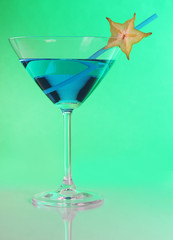 Blue cocktail in martini glass on green background