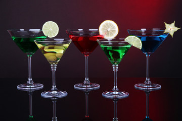 Alcoholic cocktails in martini glasses on dark red background