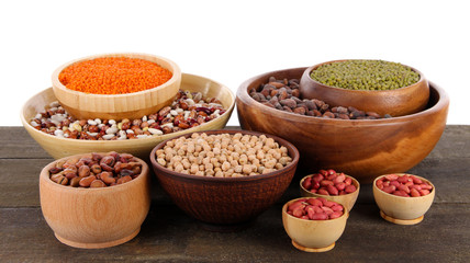 Different kinds of beans in bowls on table isolated on white