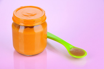 Baby food with weaning spoon on purple background