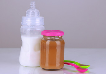 Baby food with baby supplies on grey background
