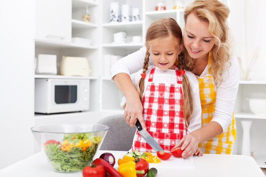 Woman and little girl preparing a vegetables salad