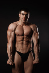Fototapeta na wymiar Young attractive man in a black bathing suit bodybuilder
