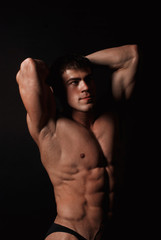 Fototapeta na wymiar Young attractive man in a black bathing suit bodybuilder