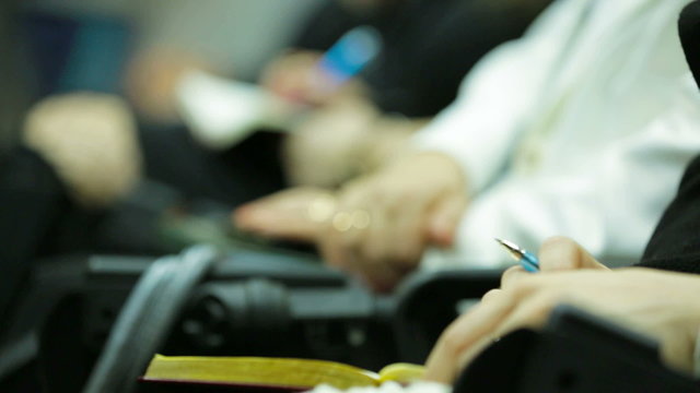 Women taking notes during a colloquium. Close-up