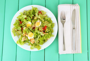 Caesar salad on white plate, on color wooden background