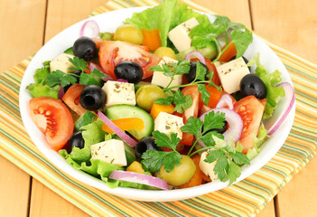Fresh salad in plate on wooden table