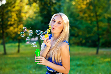 pretty blond girl blow soap bubbles outdoor