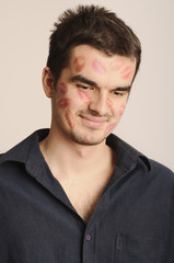 Fototapeta premium Cute guy with lipstick kisses on face