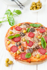 round pizza with slices of salami on white boards