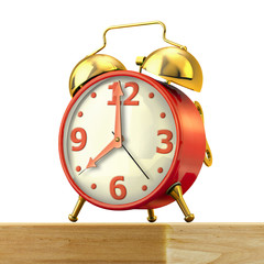 Classic alarm clock with red body and golden bells, on a wood ta