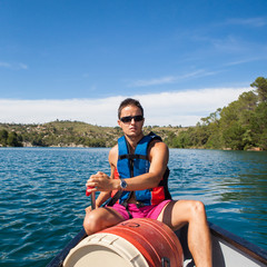 Handsome young man on a canoe on a lake, paddling, enjoying a lo