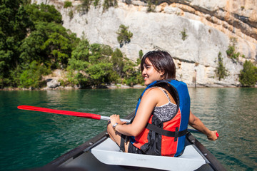 Pretty, young woman on a canoe on a lake, paddling, enjoying a l