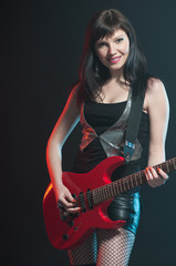 Obraz na płótnie Canvas Smiling caucasian woman playing the electric guitar, studio shot