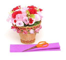 Paper flower in a basket with colorful paper and scissors