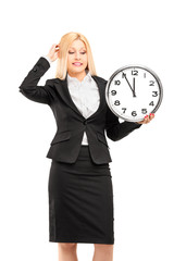 A young businesswoman holding a wall clock in her hand and gestu