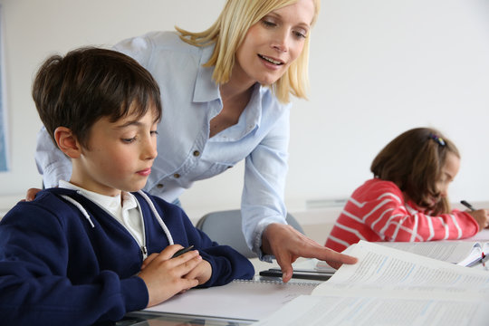 Teacher looking at classbook with young boy