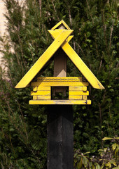 Gelbes Vogelhäuschen aus Holz auf einem Pfahl