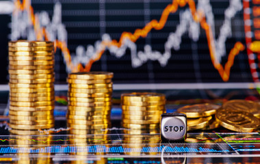 Downtrend golden coins stacks, dices cube with the word STOP and