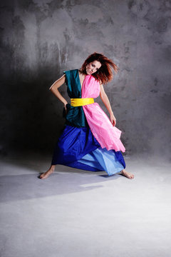 Young modern dancing girl in colorful dress on the dirty grunge
