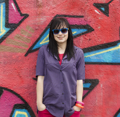 Style teen girl standing near graffiti wall.