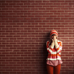 Portrait of young beautiful girl against red brick wall