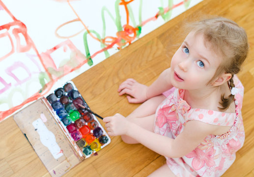 Pretty little girl painting sitting on the floor. Top view
