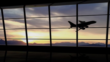 Airport window with airplane flying at sunset