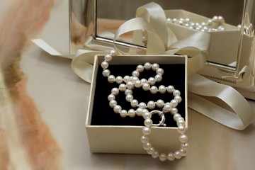 Pearl necklace in a gift box in front of a mirror