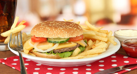 Tasty cheeseburger with fried potatoes and cold drink,