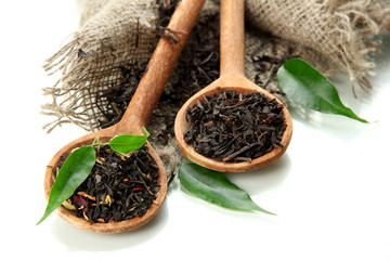 Dry tea with green leaves in wooden spoons, isolated on white