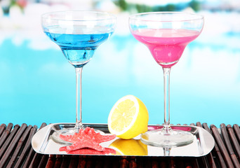 Glasses of cocktails on table near pool