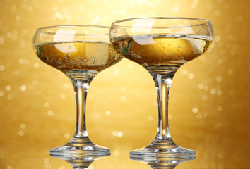 Two glasses of champagne on bright background with lights