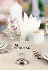 Reserved sign on restaurant table with empty dishes and glasses