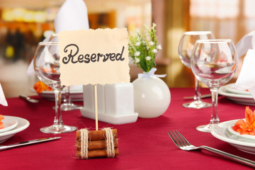 Reserved sign on restaurant table with empty dishes and glasses