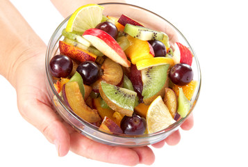 Women's hands holding bowl with fresh fruits salad on white back