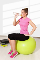 Young beautiful woman drinking water during workout