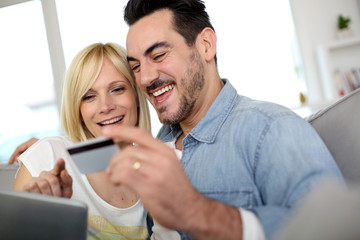 Cheerful couple at home doing online shopping