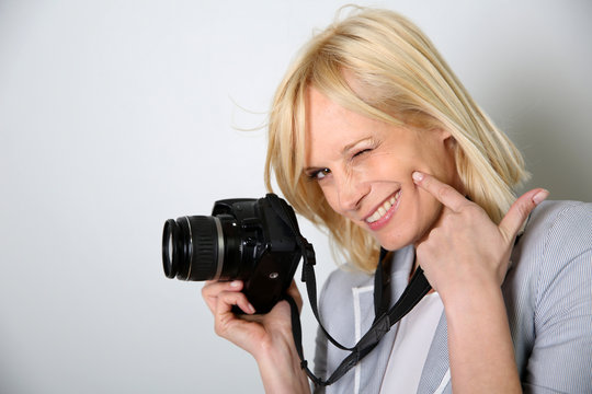 Cheerful woman photographer holding camera