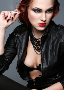  portrait of redheaded girl is in a black jacket, smoking 