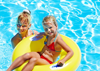 Children sitting on inflatable ring in water.