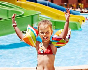 Child with armbands playing in swimming pool.