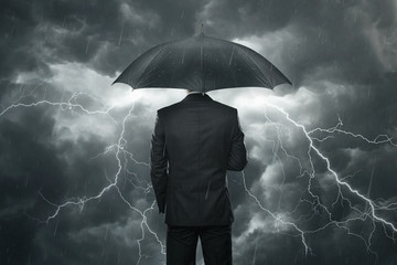 Businessman with umbrella standing in the rain