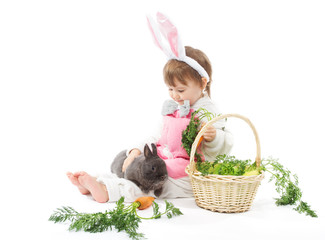 Child in bunny hare costume holding rabbit and carrot.