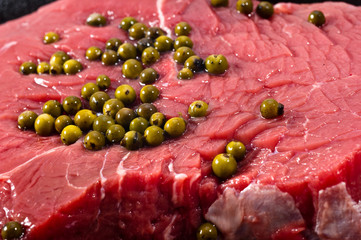 Closeup of raw beef decorated with green pepper grains